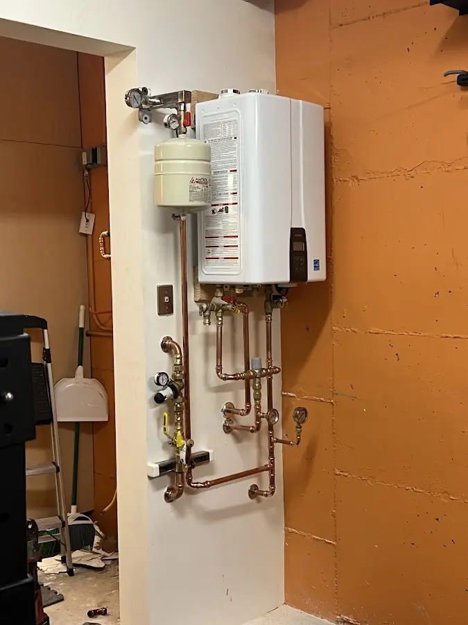 Plumbing technician inspecting water heater connections in Omak